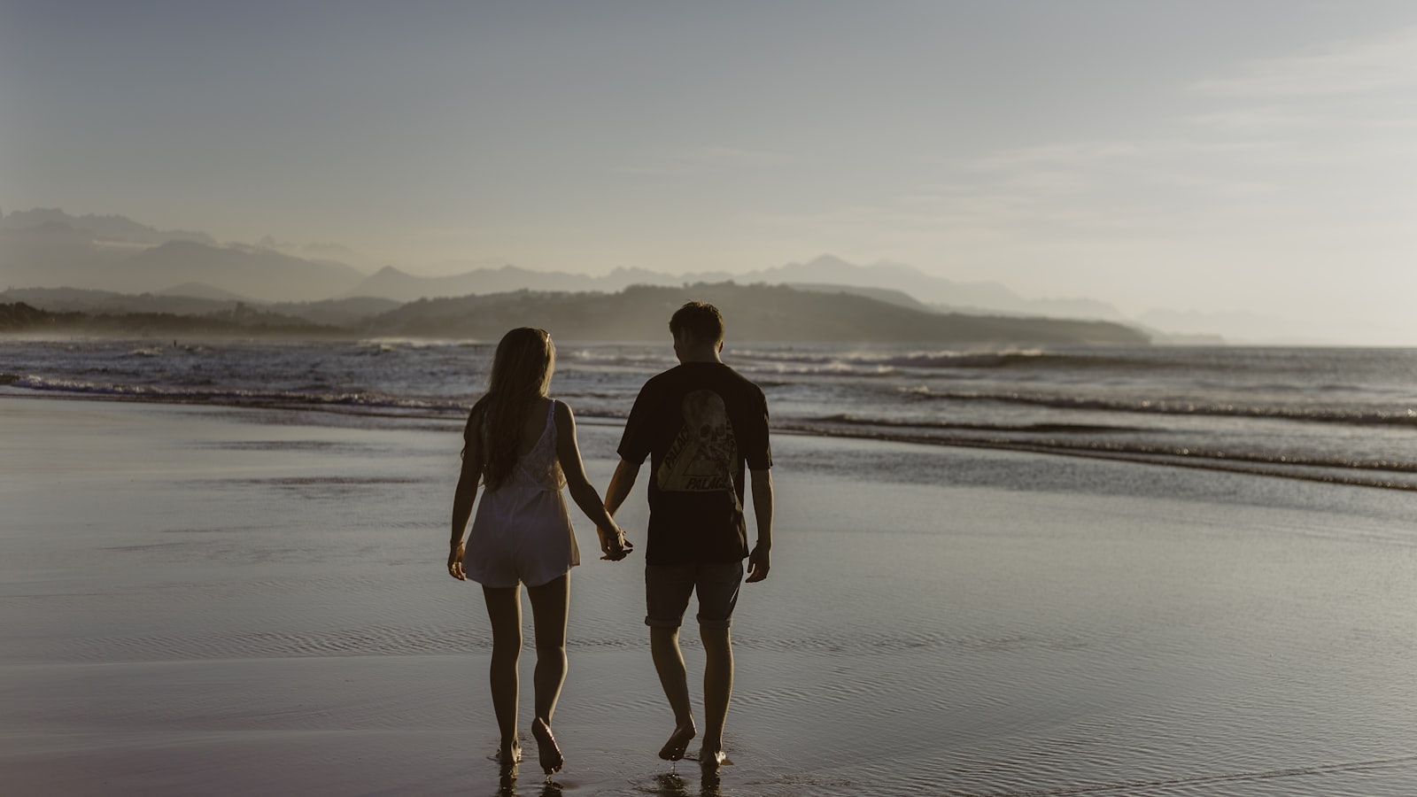 Pareja caminando por la playa al atardecer