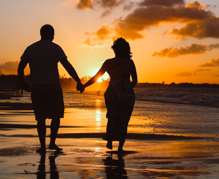 Pareja caminando por la playa al atardecer